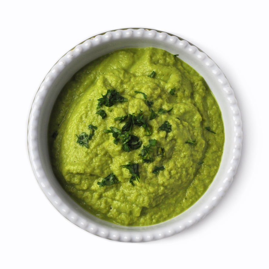 Image of a bowl with lime green colored salsa verde in it, topped with finely chopped cilantro on a white background