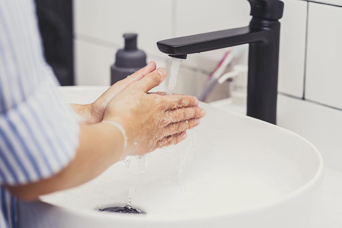 Image of a woman washing her hands in a bathroom sink that is equipped with a faucet aerator