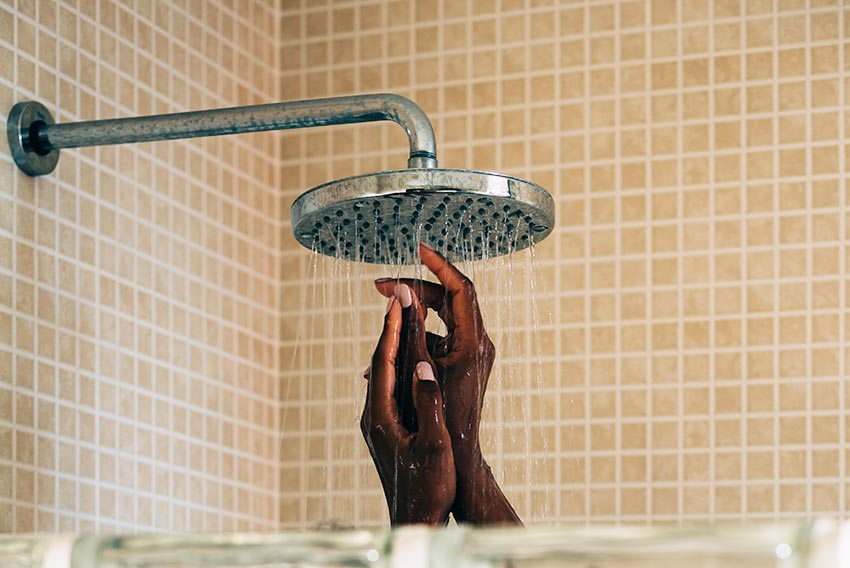 Image of a woman's hands coming up from a shower with a rain shower head