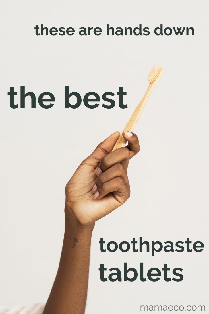 A black woman's hand holding a bamboo toothbrush