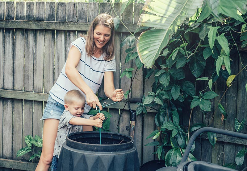 Mother and child putting food scraps into a compost